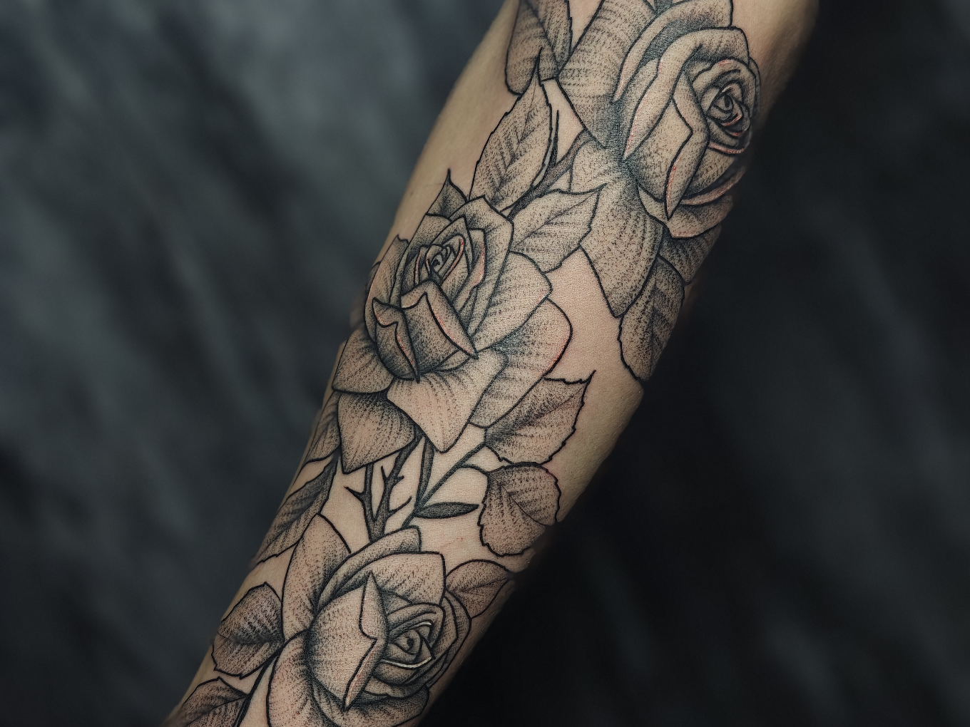 Fineline-Rosen-Tattoo mit Blättern entlang des Unterarms