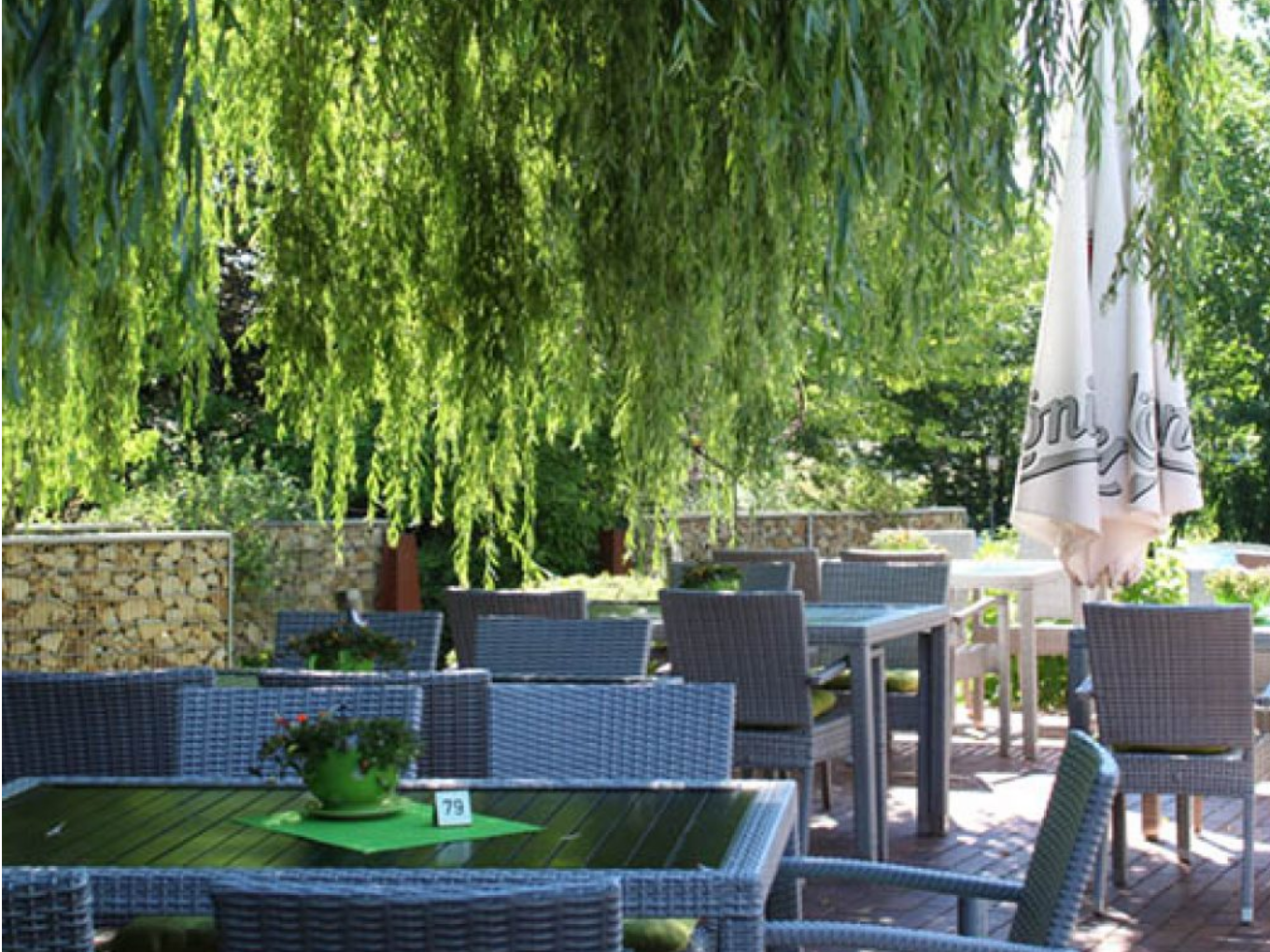 Gaststätte mit Terrasse unter schattenspendenden Bäumen