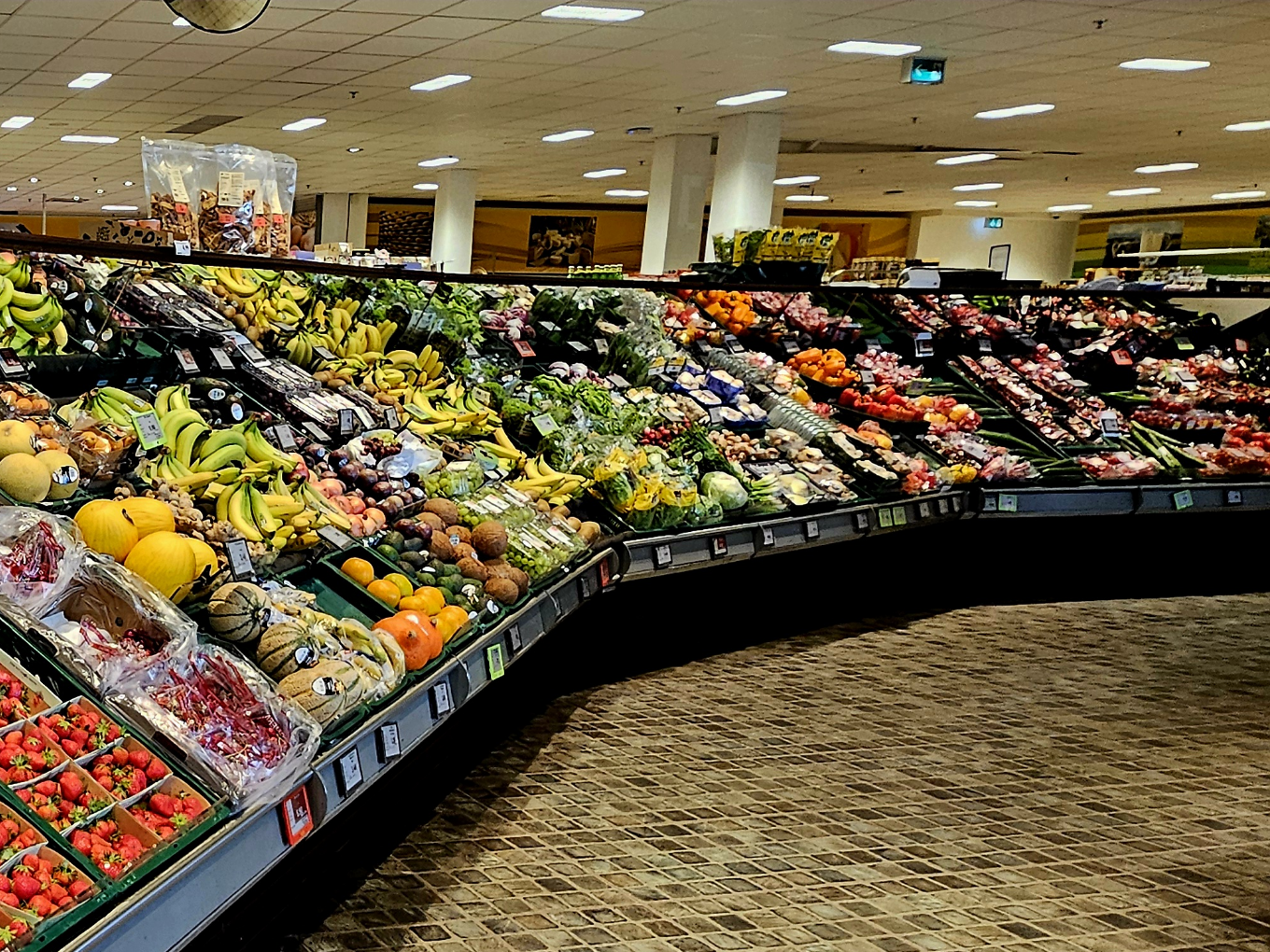 Verschiedene Sorten von frischem Obst und Gemüse, ordentlich in Regalen im Supermarkt arrangiert