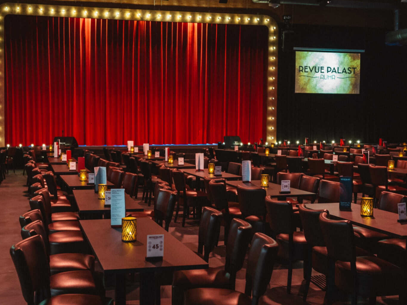 Innenraum des Revue Palast Ruhr mit roten Vorhängen und Tischen