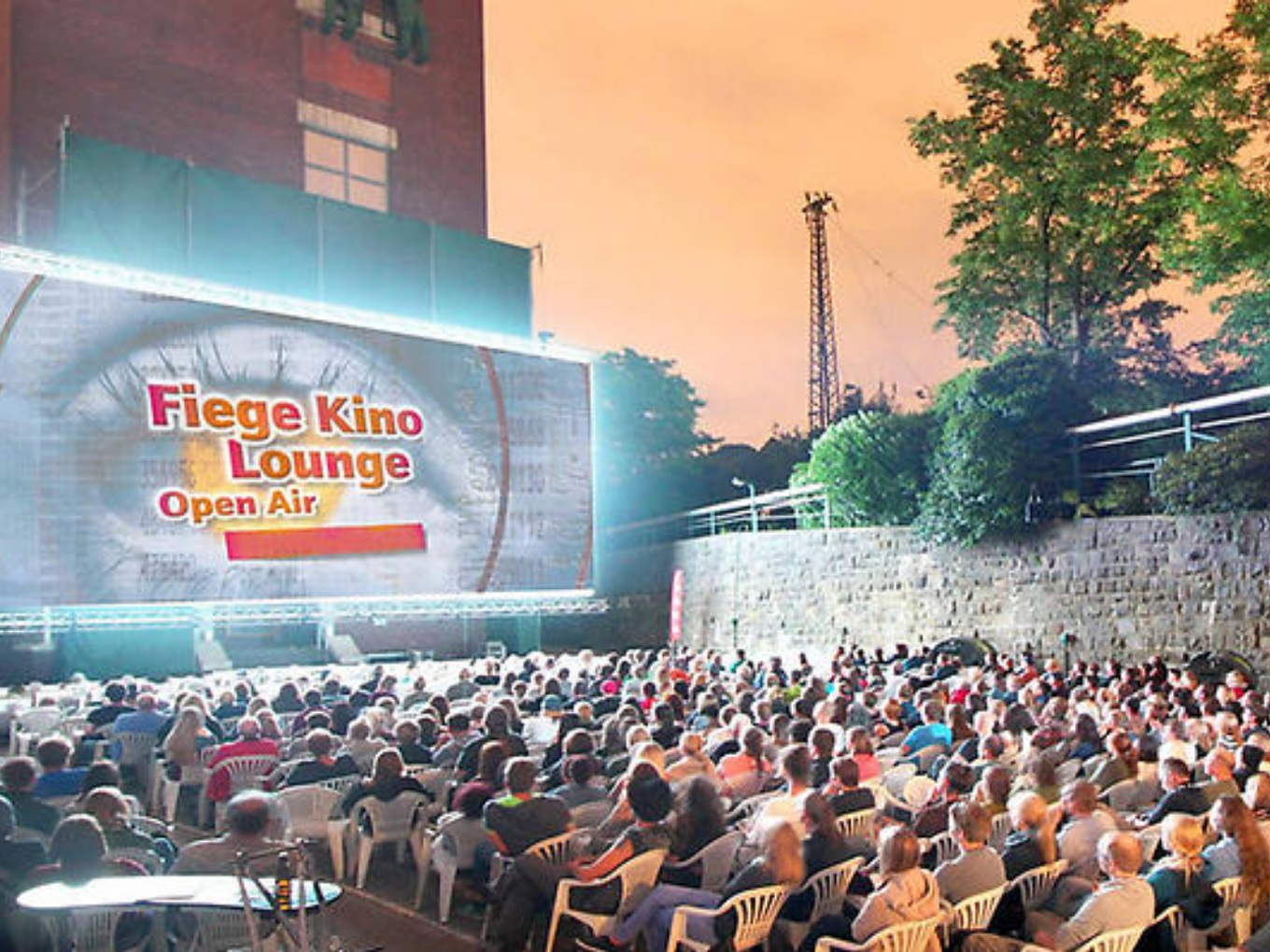 Fiege Kino Lounge Open Air: Viele Besucher sitzen abends vor einer großen Kinoleinwand im Freien.