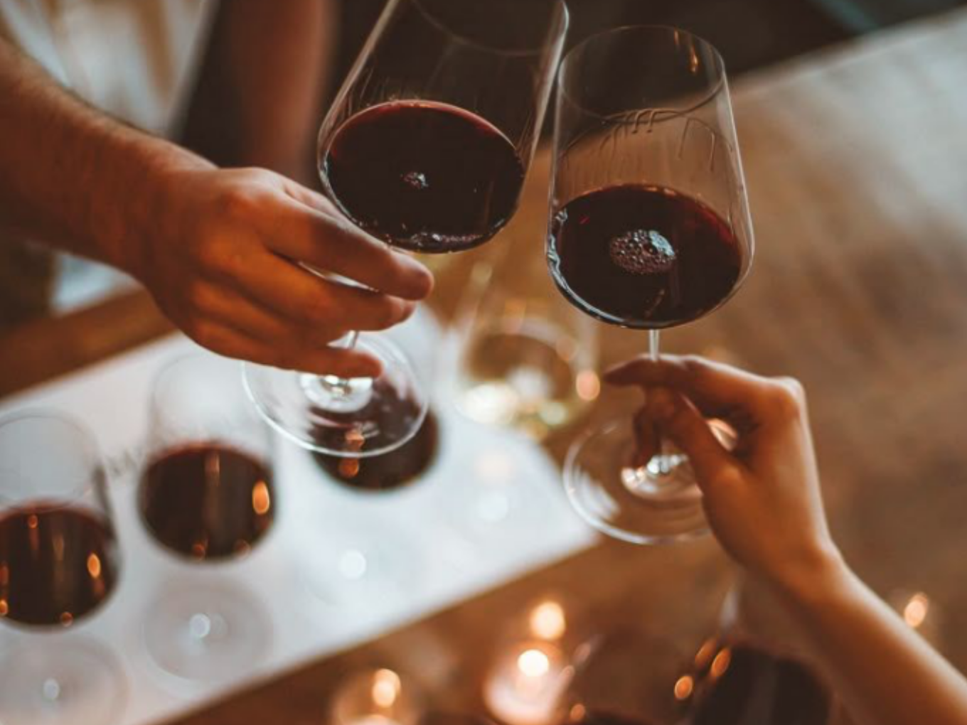 Zwei Gäste stoßen beim Winzerfest im Restaurant Am Jäger mit Gläsern Rotwein an.