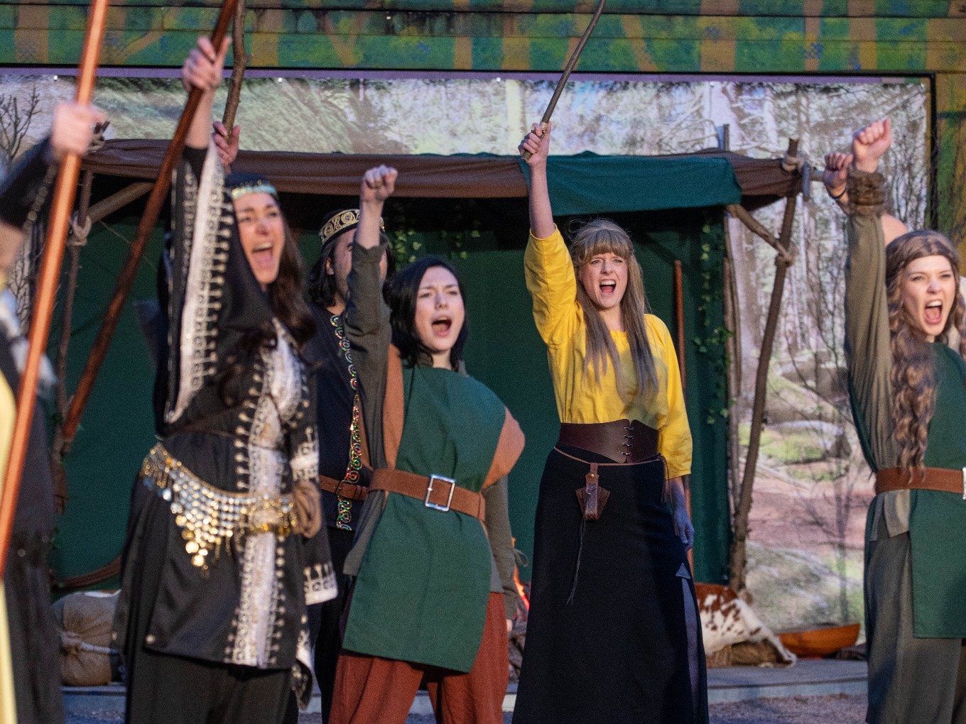 Frauen des Robin-Hood-Ensembles jubeln mit erhobenen Stäben.