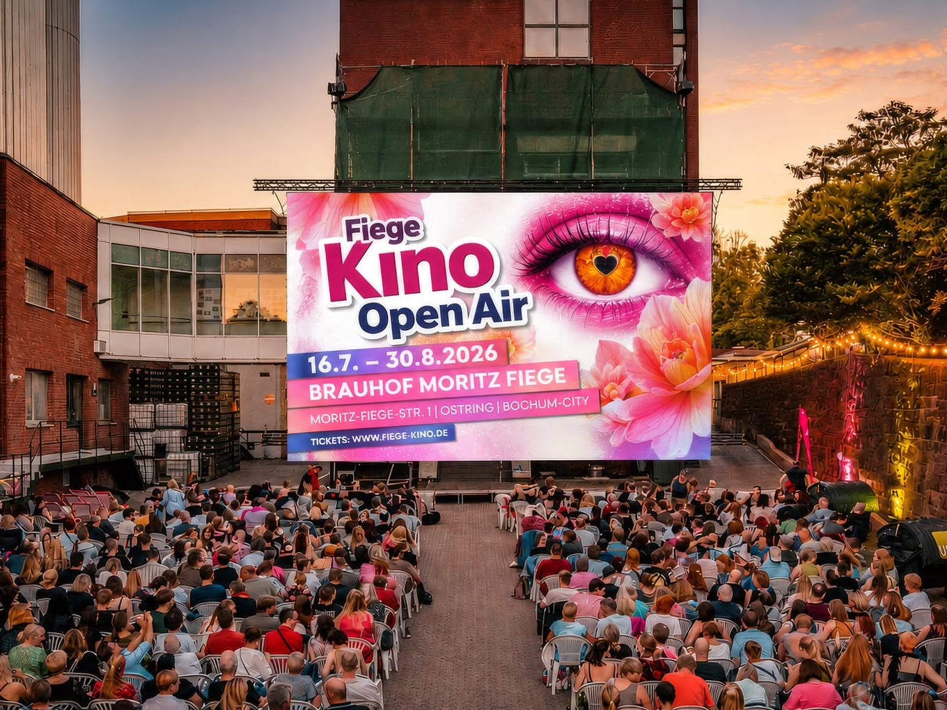 Open-Air-Kino mit vielen Zuschauern vor einer großen Leinwand, auf der für das Fiege Kino Open Air 2026 geworben wird.