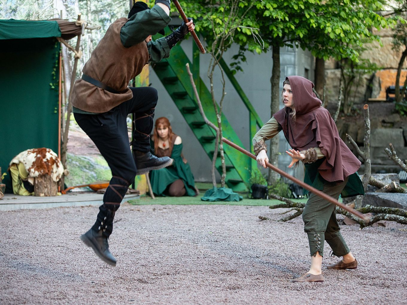Zwei Darsteller kämpfen in einer Robin-Hood-Szene mit langen Stäben.