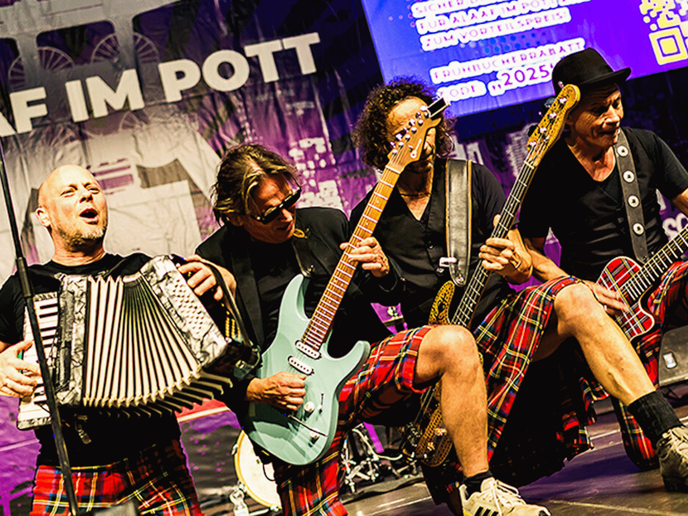 Bandmitglieder spielen Akkordeon, Gitarren und Bass auf Bühne mit 'Alaaf im Pott' Banner