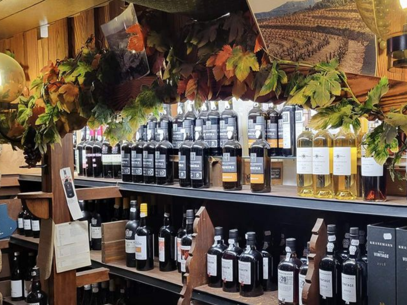 Regal mit verschiedenen Portwein- und Likörflaschen, dekoriert mit Weinlaub.