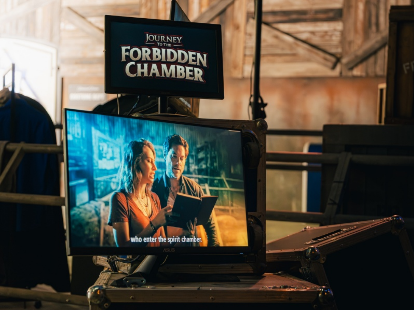 Ein Monitor zeigt einen Filmausschnitt mit zwei Menschen, darüber ein Schild mit der Aufschrift „Journey to the Forbidden Chamber“.