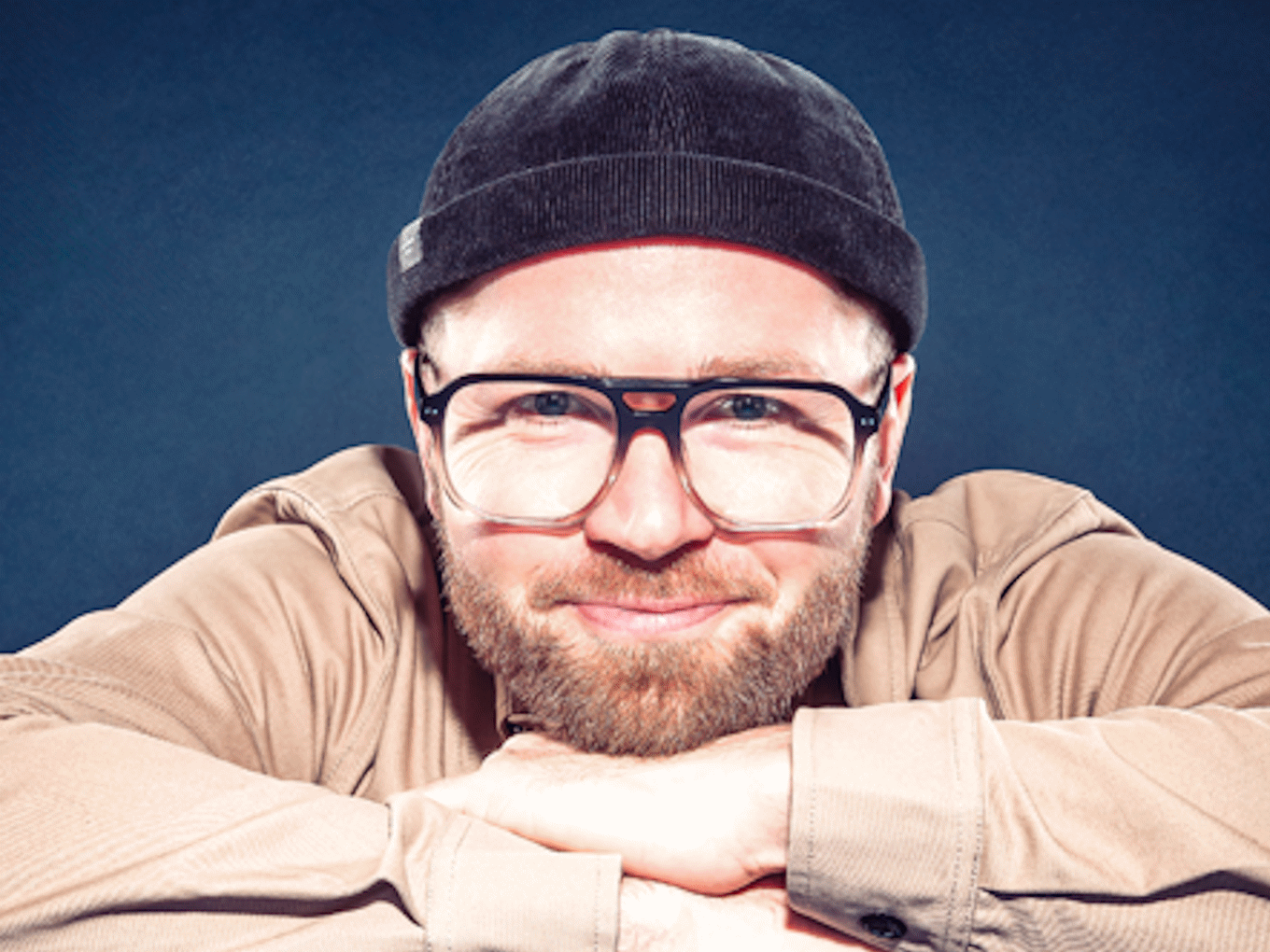 Portrait von Hannes Höfer vor blauem Hintergrund mit blauer Mütze