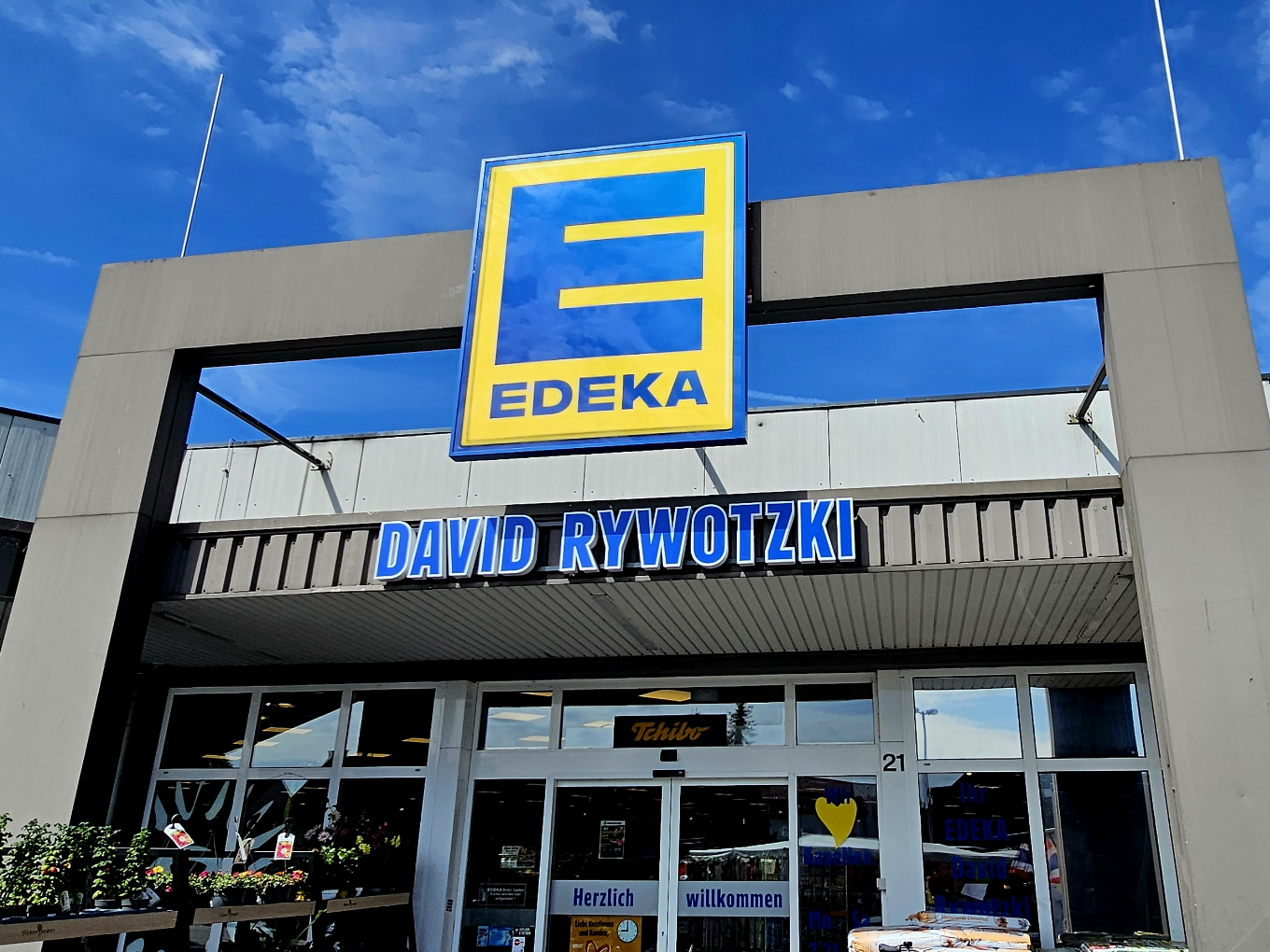 EDEKA Logo an der Fassade des Eingangs des Marktes David Rywotzki unter blauem Himmel