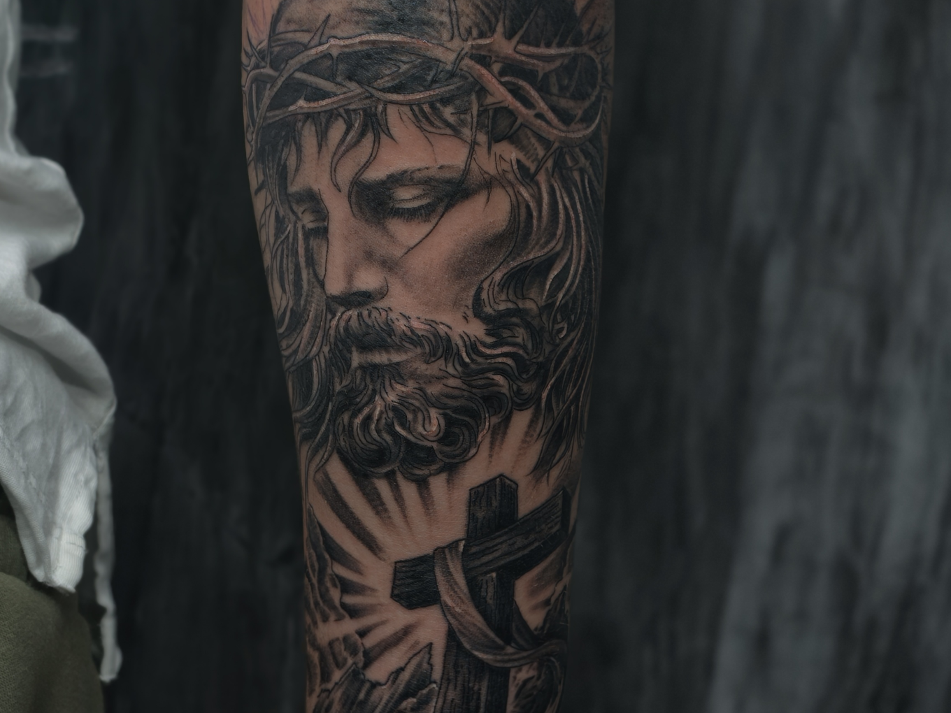 Black-and-Grey-Tattoo von Jesus mit Dornenkrone und Kreuz am Unterarm