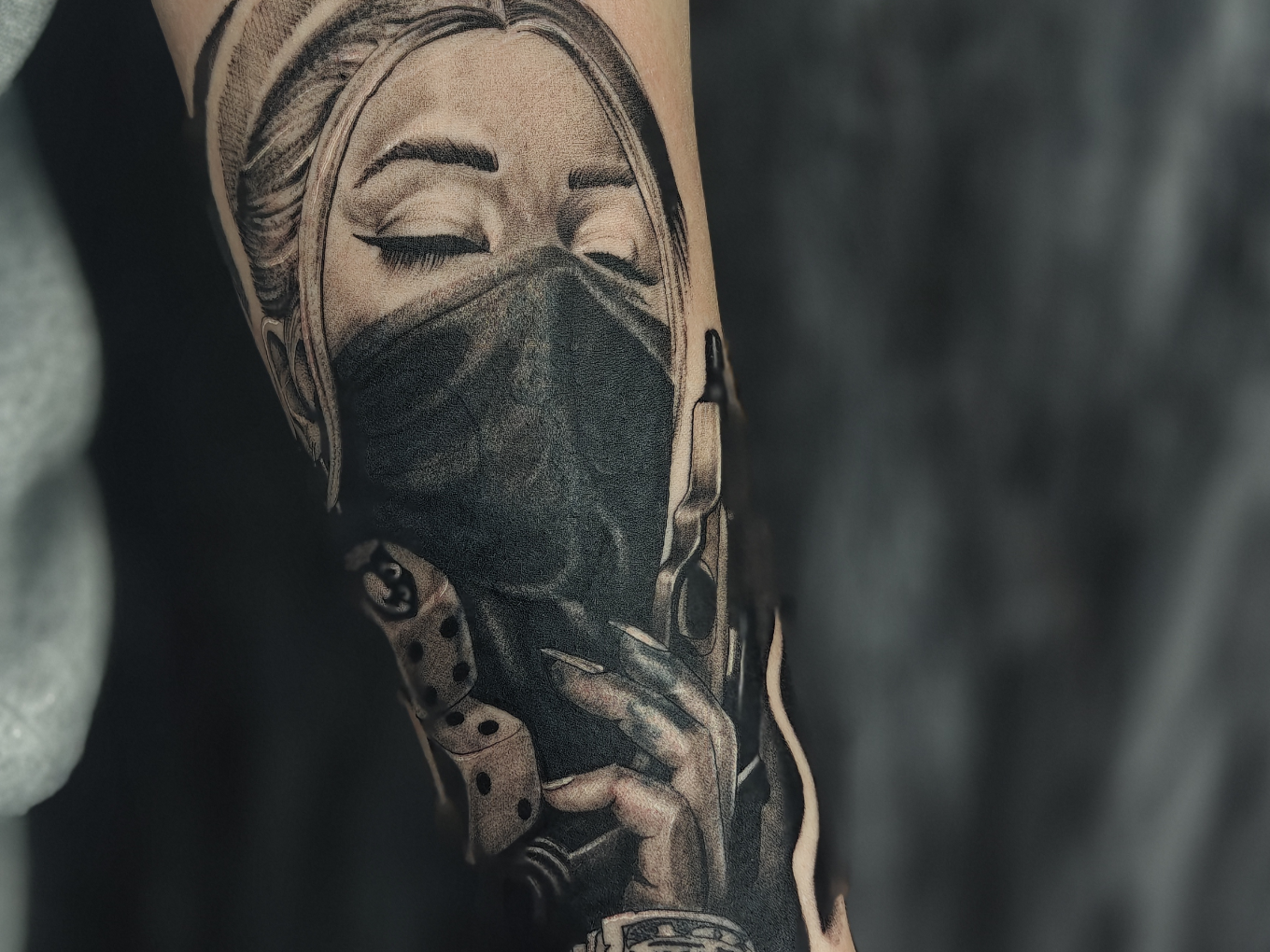 Black-and-Grey-Tattoo einer maskierten Frau mit Spielwürfeln und Pistole
