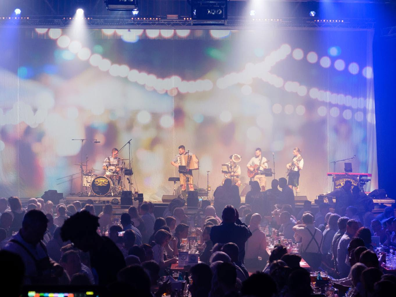 Live-Band auf der Bühne beim Oktoberfest Hagen, feierndes Publikum in der Stadthalle.