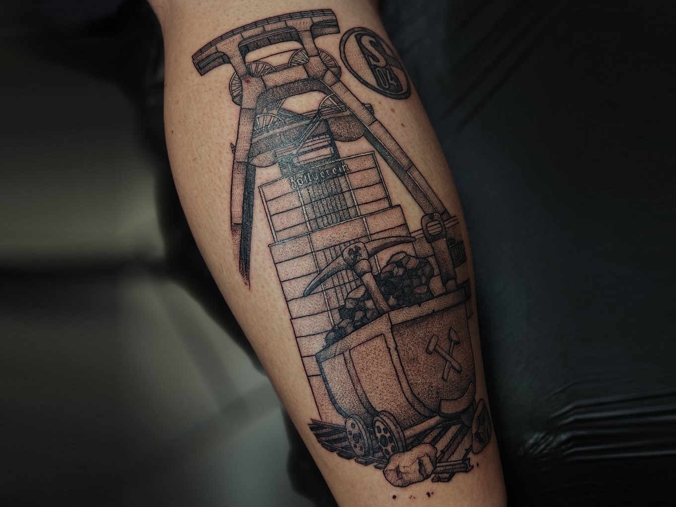 Detailreiches Fineline-Tattoo eines Förderkorbs mit Bergbau-Motiven