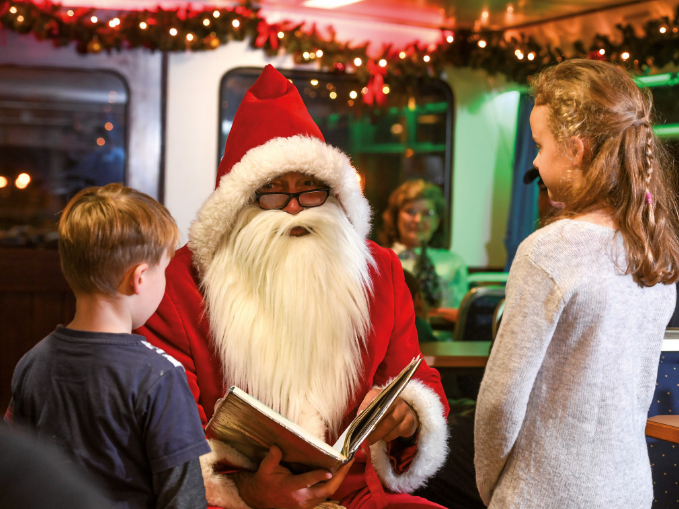 Nikolaus liest Kindern auf einem festlich geschmückten Schiff eine Geschichte vor.