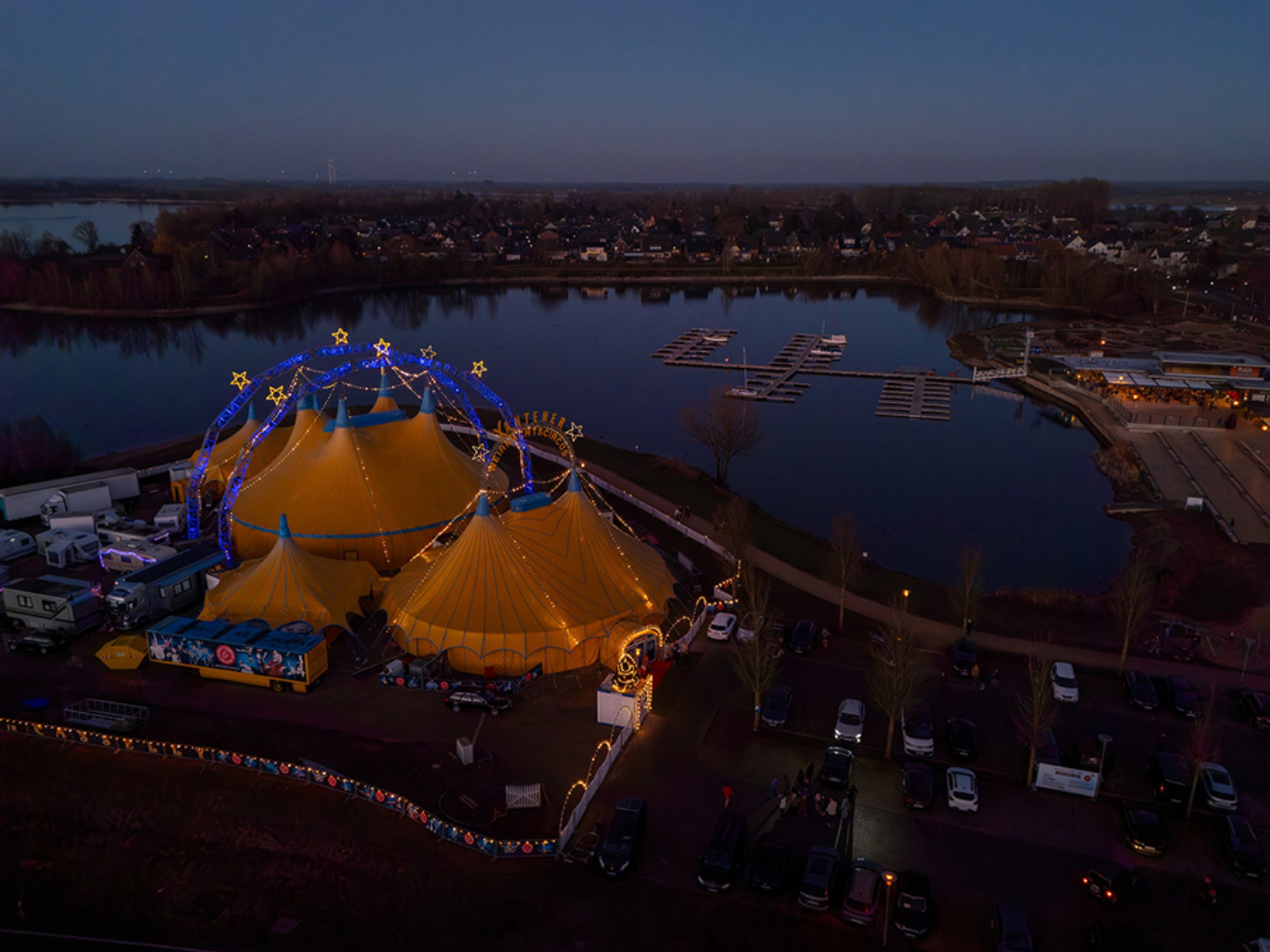 Weihnachtscircus mit beleuchtetem Zelt am See bei Dämmerung