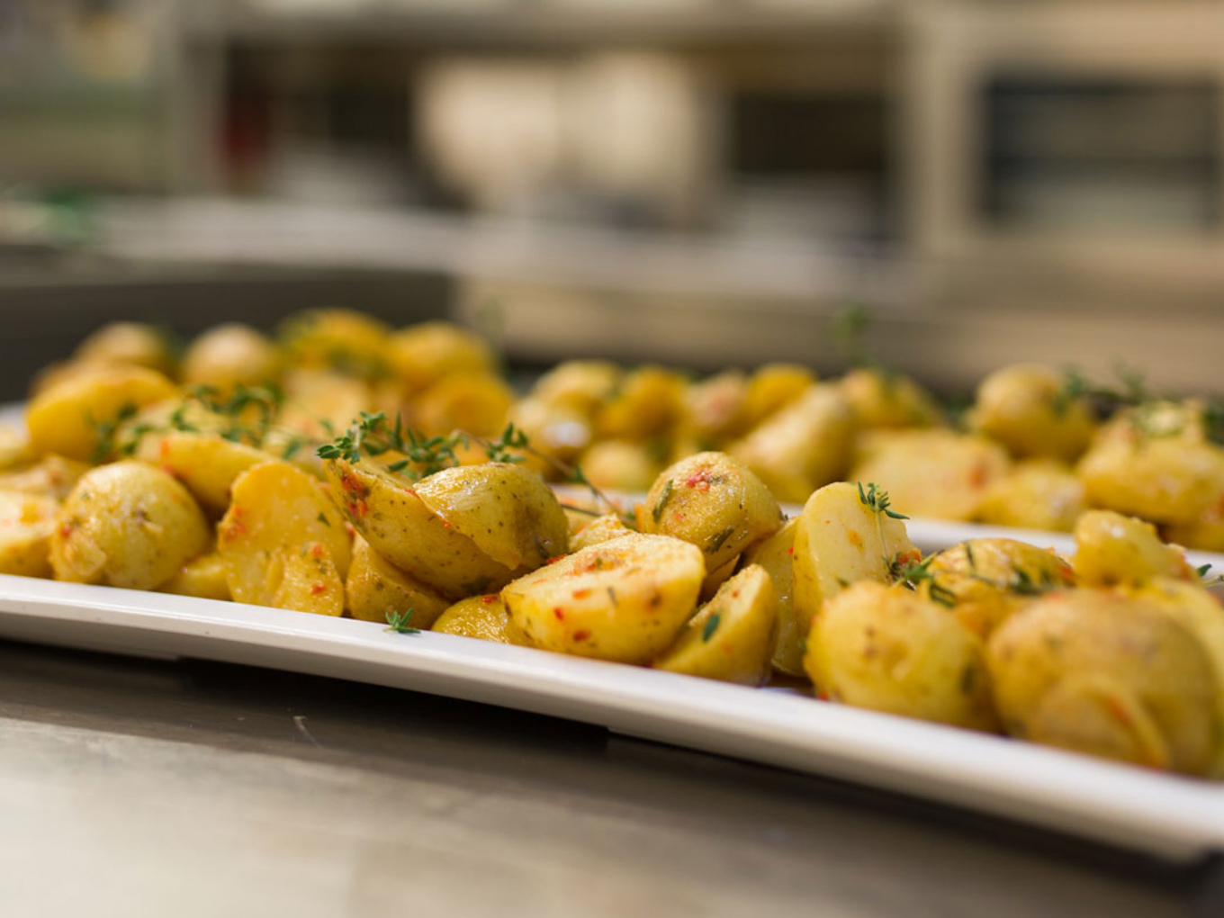 Gebratene Kartoffeln mit Kräutern auf einem weißen Teller.