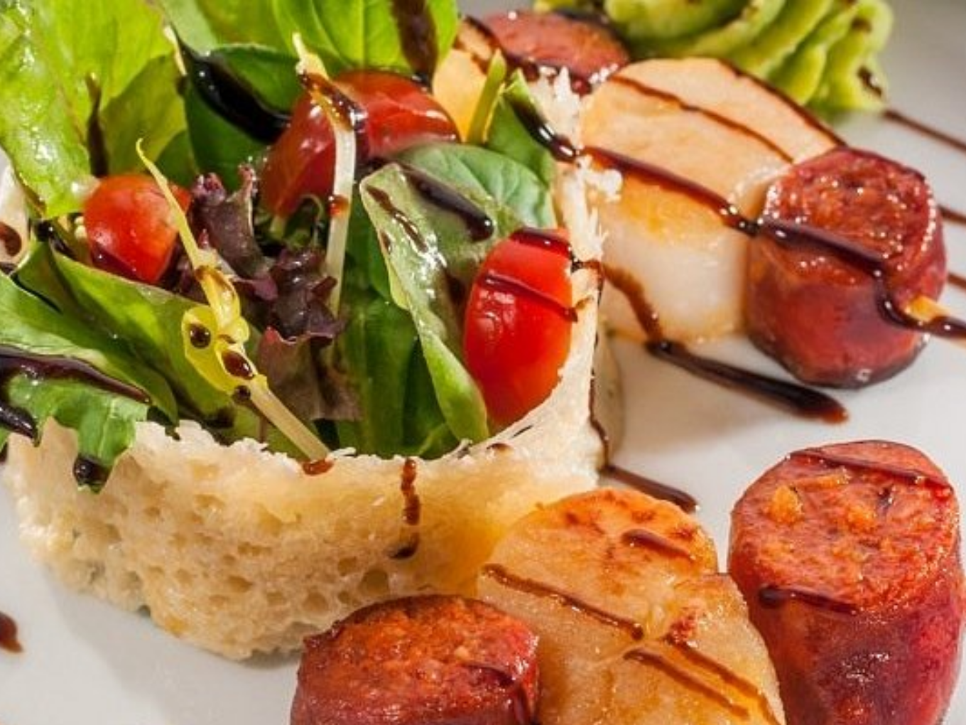 Salat im Parmesan-Körbchen, gebratene Jakobsmuscheln und Chorizo, garniert mit Balsamico.